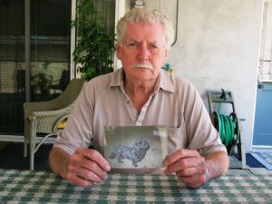 Don Peck holding picture of his dog Kiwi